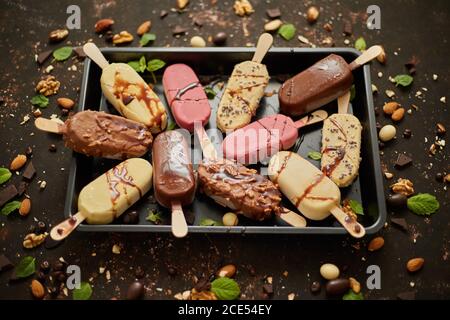 Ensemble de délicieux chocolat blanc et au lait et glace à la fraise sur un bâton servi dans un plateau métallique Banque D'Images