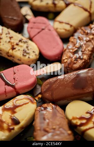 Crème glacée sur bâton recouverte de divers glaçures de chocolat et garnitures. Vue de dessus, plan d'appartement Banque D'Images