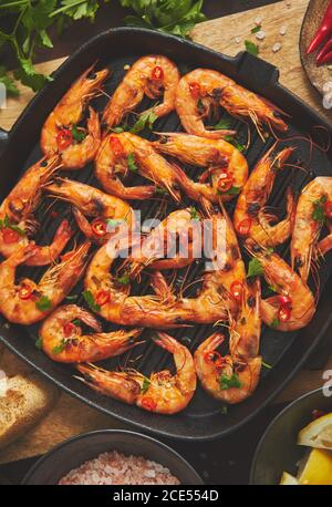 Crevettes tigrées grillées sur une poêle à gril en fer avec de la vermicelles, du citron, du piment et du pain frais Banque D'Images