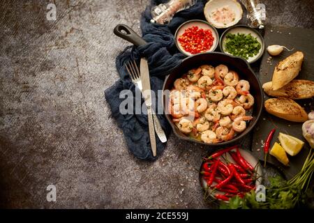 Crevettes grillées dans une poêle en fonte avec citron frais, persil, piment et sauce au vin blanc à l'ail Banque D'Images