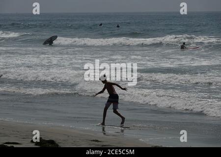 Une silhouette d'un garçon écume à proximité du bord de l'océan sur la plage. Banque D'Images