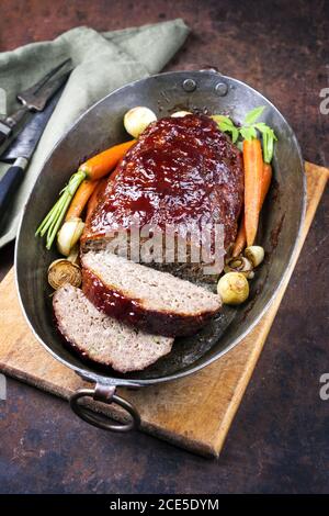 Pain de viande américain traditionnel avec ketchup de bœuf haché et carottes et l'oignon comme gros plan dans une casserole en cuivre Banque D'Images