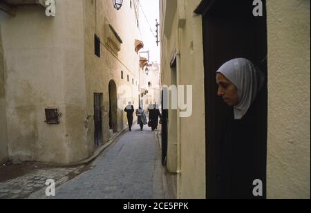 14.11.2010, Fès, Maroc, Afrique - UNE femme se tient à la porte d'une maison dans la médina historique avec ses ruelles étroites, un site classé au patrimoine mondial de l'UNESCO. Banque D'Images