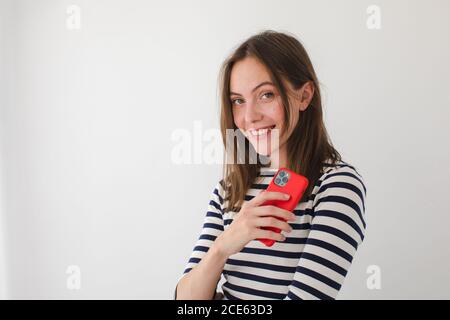 Femme souriante surfant sur un smartphone à la maison Banque D'Images