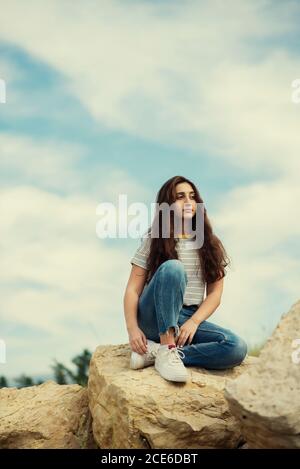 Adolescente assise sur des rochers à l'extérieur Banque D'Images