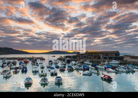 Lyme Regis, Dorset, Royaume-Uni. 31 août 2020. Météo Royaume-Uni. TH nuages au-dessus de Cobb Harbour brillent orange au lever du soleil à Lyme Regis dans Dorset sur la banque de vacances lundi. Crédit photo : Graham Hunt/Alamy Live News Banque D'Images