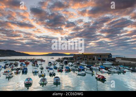 Lyme Regis, Dorset, Royaume-Uni. 31 août 2020. Météo Royaume-Uni. TH nuages au-dessus de Cobb Harbour brillent orange au lever du soleil à Lyme Regis dans Dorset sur la banque de vacances lundi. Crédit photo : Graham Hunt/Alamy Live News Banque D'Images