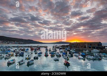 Lyme Regis, Dorset, Royaume-Uni. 31 août 2020. Météo Royaume-Uni. TH nuages au-dessus de Cobb Harbour brillent orange au lever du soleil à Lyme Regis dans Dorset sur la banque de vacances lundi. Crédit photo : Graham Hunt/Alamy Live News Banque D'Images