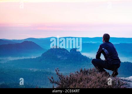 Homme calme assis au sommet de la montagne en profitant de la vue Banque D'Images