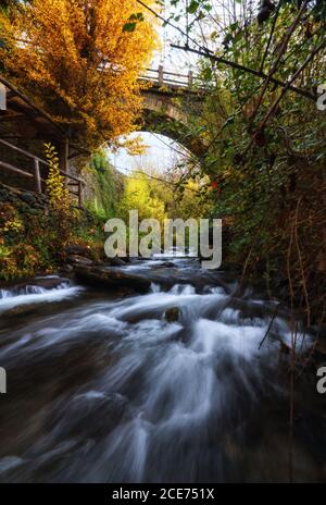 Paysage majestueux de la rivière qui coule à travers la forêt et sous le pont En longue exposition à Grenade Banque D'Images