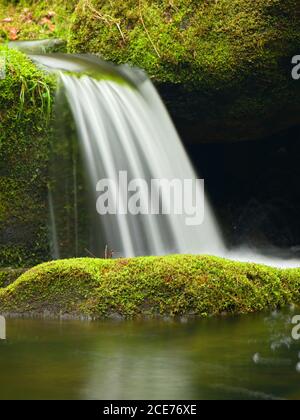 Cascade sur un petit ruisseau de montagne. L'eau froide de cristal tombe au-dessus des blocs de mousse de basalte dans une petite piscine. Banque D'Images