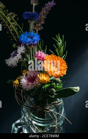 Grand angle de bouquet de fleurs colorées placé dans le verre coupe sur fond noir en studio Banque D'Images