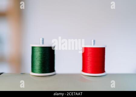 Kit de rouleaux de fils en vert vif et rouge de matériau naturel avec surface brillante en atelier sur blanc arrière-plan Banque D'Images