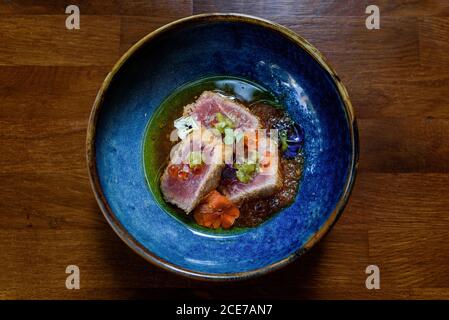 Du dessus du bol avec du thon ahi saisi garni de caviar et herbes et placé sur une table en bois dans le café Banque D'Images