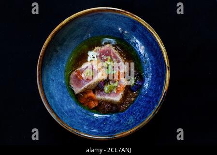 Du dessus du bol avec du thon ahi saisi garni de caviar et herbes et placé sur une table en bois dans le café Banque D'Images