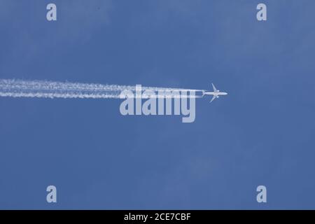 Un avion passager haut dans le ciel avec chemins de chemin avec un ciel bleu Banque D'Images