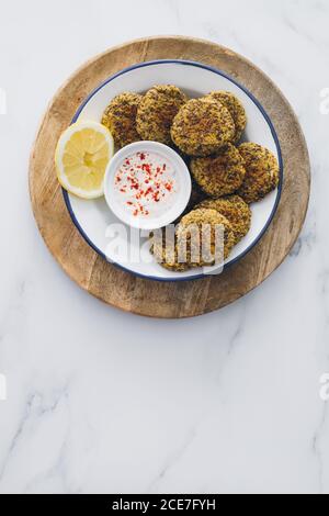 Vue de dessus d'un plat plein de falafel de lentilles servi avec sauce au yaourt sur une table en bois Banque D'Images