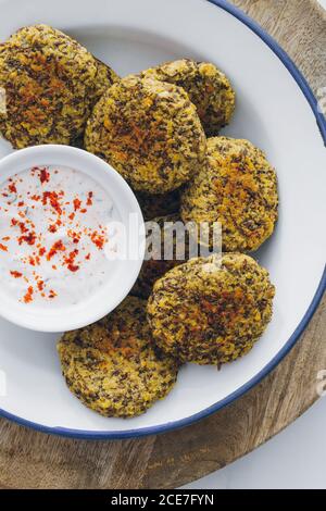 Vue de dessus d'un plat plein de falafel de lentilles servi avec sauce au yaourt sur une table en bois Banque D'Images