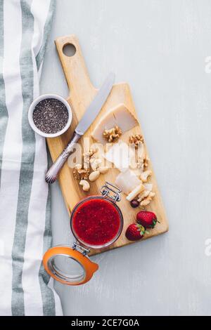 Vue d'en haut de la table avec confiture de fraises dans un pot, fromage en tranches et fromage varié servi sur bois Banque D'Images