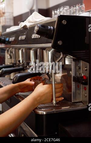 Vue latérale d'une femme Barista méconnaissable à l'aide d'une machine à café et préparation de café aromatique au café Banque D'Images