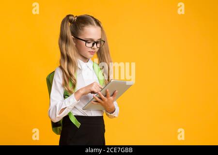 Écolière utilisant un ordinateur tablette faire école devoirs debout dans Studio Banque D'Images