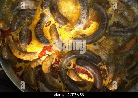 Processus de cuisson des saucisses de sang dans une casserole en fer sur feu de joie dans une usine de viande traditionnelle dans une zone rurale Banque D'Images