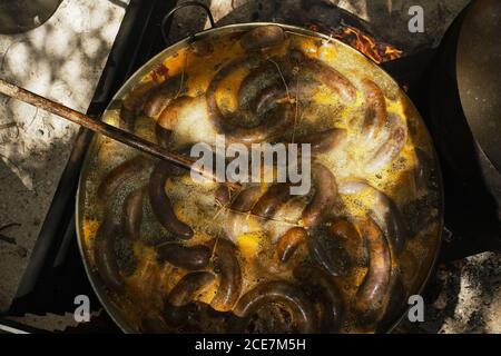 Processus de cuisson des saucisses de sang dans une casserole en fer sur feu de joie dans une usine de viande traditionnelle dans une zone rurale Banque D'Images