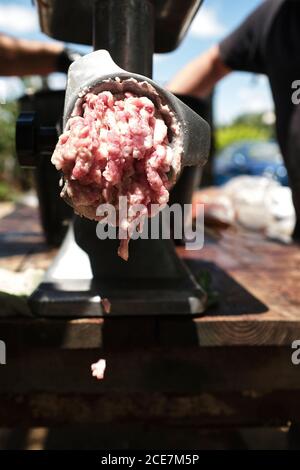 boucher mâle non reconnaissable utilisant la machine à hacher pendant le broyage de la viande à usine locale d'abattage Banque D'Images