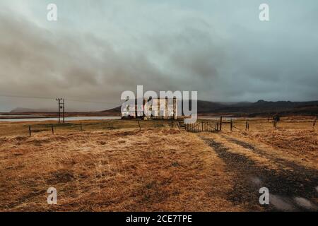 Ancienne construction partiellement détruite dans le champ près des montagnes couvertes de Brouillard sous le ciel avec des nuages bas en automne en Islande Banque D'Images