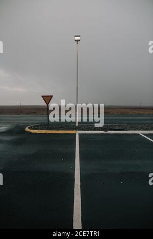 Vider la route asphaltée avec des marques blanches passant par la pelouse sèche Champ en Islande contre les nuages épais Banque D'Images