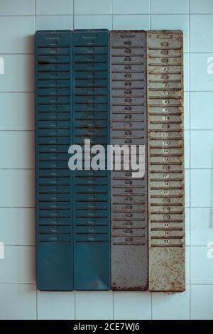 Boîtes aux lettres en métal rouillé placées sur un mur en carrelage de l'abandon des intempéries bâtiment pendant la journée Banque D'Images