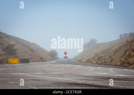 Rond de signalisation routière d'interdiction rouge avec le mot STOP sur vide chaussée asphaltée sur terrain rural sec Banque D'Images