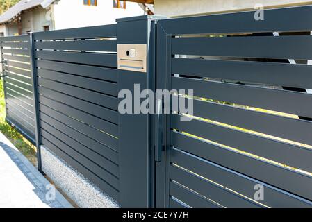 Un visiophone moderne avec boîte aux lettres et lecteur de cartes sans fil, monté dans une clôture de panneau en anthracite, porte-affiche visible. Banque D'Images