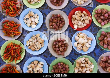 Vue de dessus de l'ail et des oignons dans les bols placés dessus comptoir avec piments séchés dans le bazar local Banque D'Images