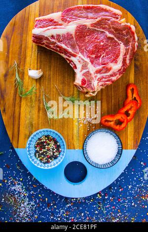 Viande de bœuf crue sur la table, épices et ingrédients pour le romarin et le steak de côtes. Poivre et gros sel Banque D'Images