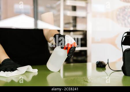 Par le biais de la récolte de verre concentré femme caissière portant un respirateur et le latex gants essuyant le comptoir avec un chiffon tout en travaillant dans le café à prévenir la propagation du coronavirus Banque D'Images