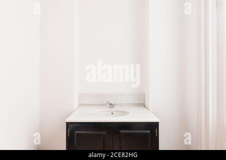 Porte ouverte en bois avec ornement et bouton doré dans moderne salle de bains avec meuble-lavabo en forme de carré avec évier rond et robinet en acier inoxydable près du mur blanc Banque D'Images