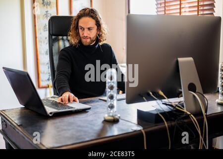 Beau homme travaillant à l'ordinateur de bureau à la maison Banque D'Images