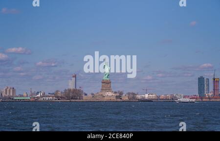 Vue magnifique sur la statue colossale de la liberté située sur Liberty Île de New York contre ciel bleu ciel nuageux au printemps jour Banque D'Images