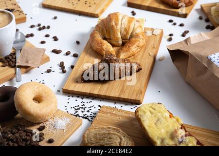 Vue de dessus de la table du petit déjeuner pleine de pâtisseries variées, sandwiches et café servis sur des planches de bois Banque D'Images