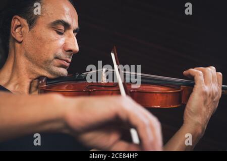 Violoniste hispanique de talent jouant du violon et regardant la musique feuilles pendant la répétition Banque D'Images