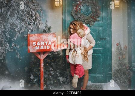 maman et fille vérifient la boîte aux lettres et attendent une lettre du père noël. miracle à noël. bonne année Banque D'Images