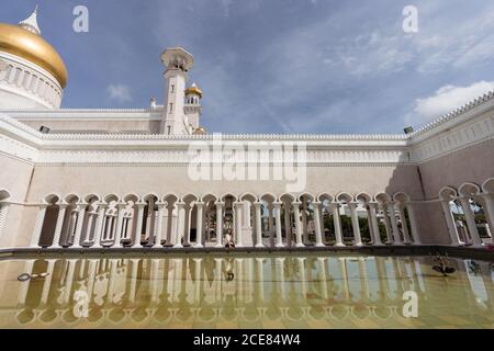 Vue latérale sur les touristes asiatiques assis à la frontière près lac près de la mosquée Omar Ali Saifuddien et vue loin pendant Vacances d'été au Brunei Banque D'Images
