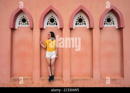 Pleine longueur de femme asiatique voyageur debout dans la fenêtre voûtée De la Mosquée rose pendant la visite à Kota Kinabalu pendant l'été vacances et vue Banque D'Images