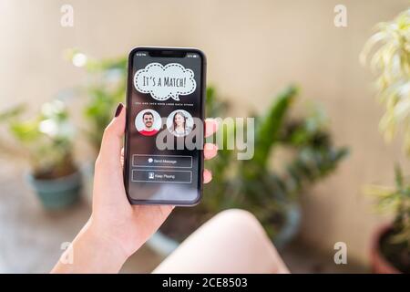 Par dessus une femme anonyme faisant la démonstration d'un smartphone moderne avec match in application datant en vous reposant sur la terrasse Banque D'Images