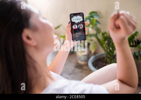 Par dessus une femme anonyme faisant la démonstration d'un smartphone moderne avec match in application datant en vous reposant sur la terrasse Banque D'Images