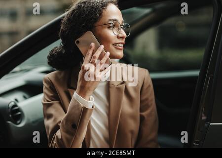 Femme d'affaires assise dans sa voiture et parlant au téléphone. Femme en tenue d'affaires qui fait un appel téléphonique en étant assise dans sa voiture. Banque D'Images