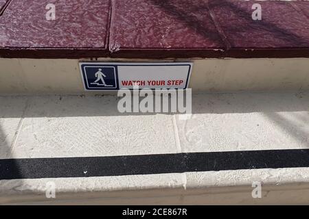 Plaque avec un panneau de rappel « Watch Your STEP » et un bande noire sur les escaliers Banque D'Images