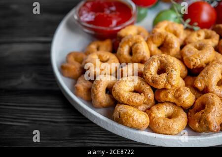 Tortellini fait à la main avec des tomates et des verts de thym sur une plaque blanche est appelé taralli. Taralli dans les boulangeries italiennes dans le sud de l'Italie sur un bois Banque D'Images