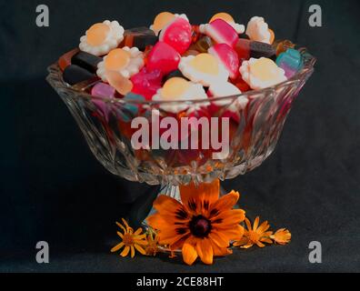 Bonbons dans un bol en verre combiné avec des fleurs. Banque D'Images